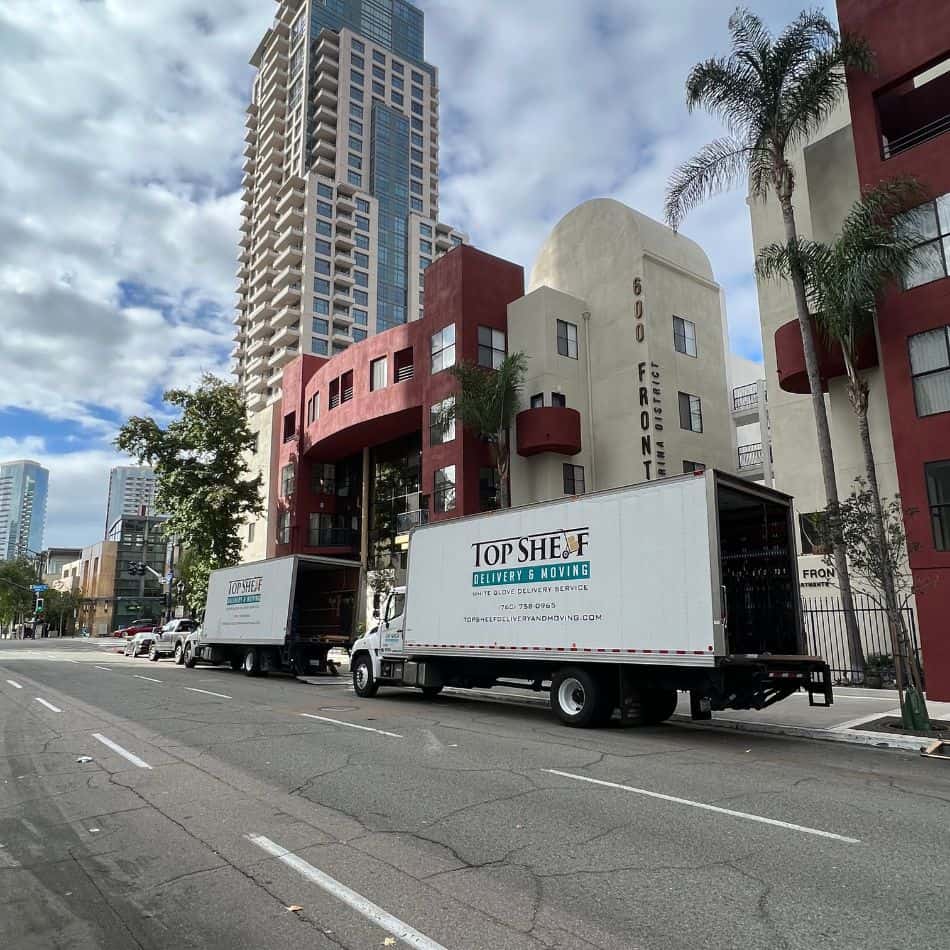 Two Top Shelf white glove delivery trucks staged for a commercial relocation in a downtown high-rise district.