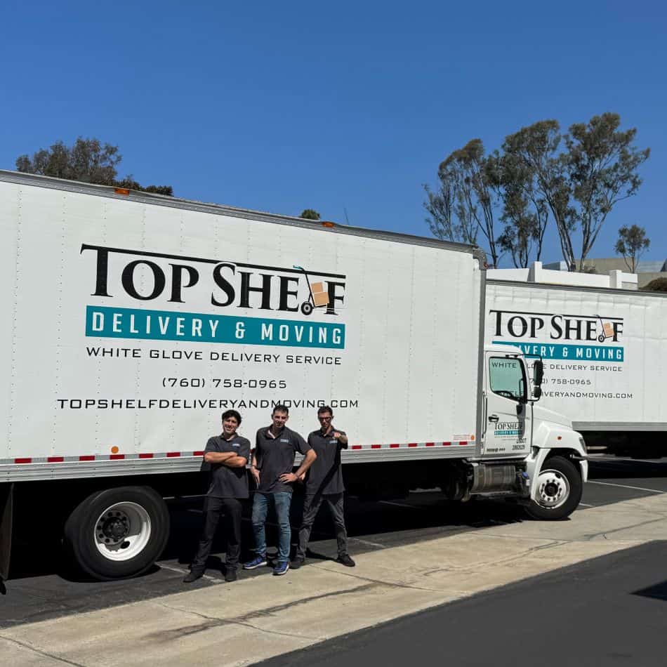 Top Shelf Delivery and Moving team posing with multiple white glove service trucks at a commercial facility.